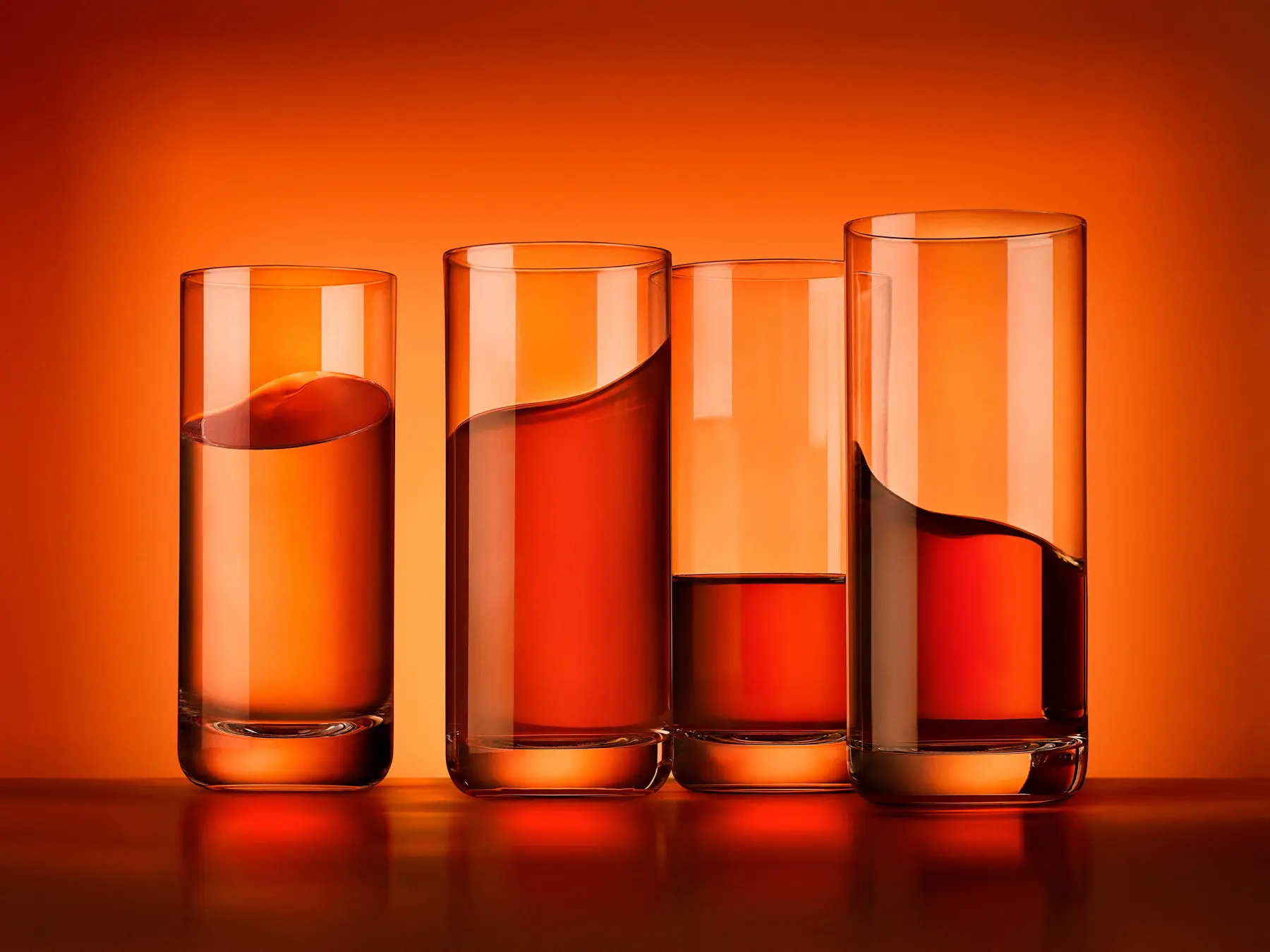Cuatro vasos de una bebida naranja sobre fondo naranja · Fotografía de producto, TimeLäB Studio Barcelona